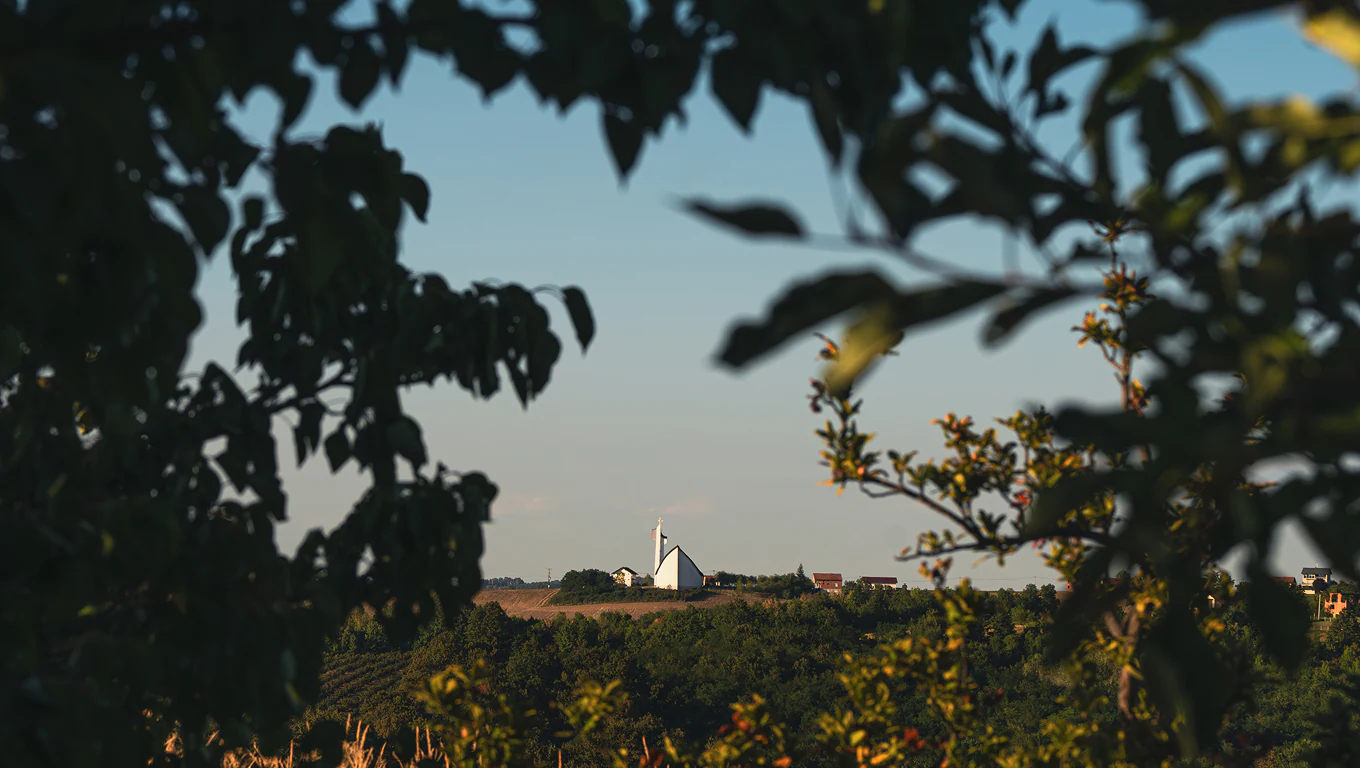Kulina countryside and church seen through fruit trees in Bosnian Posavina.