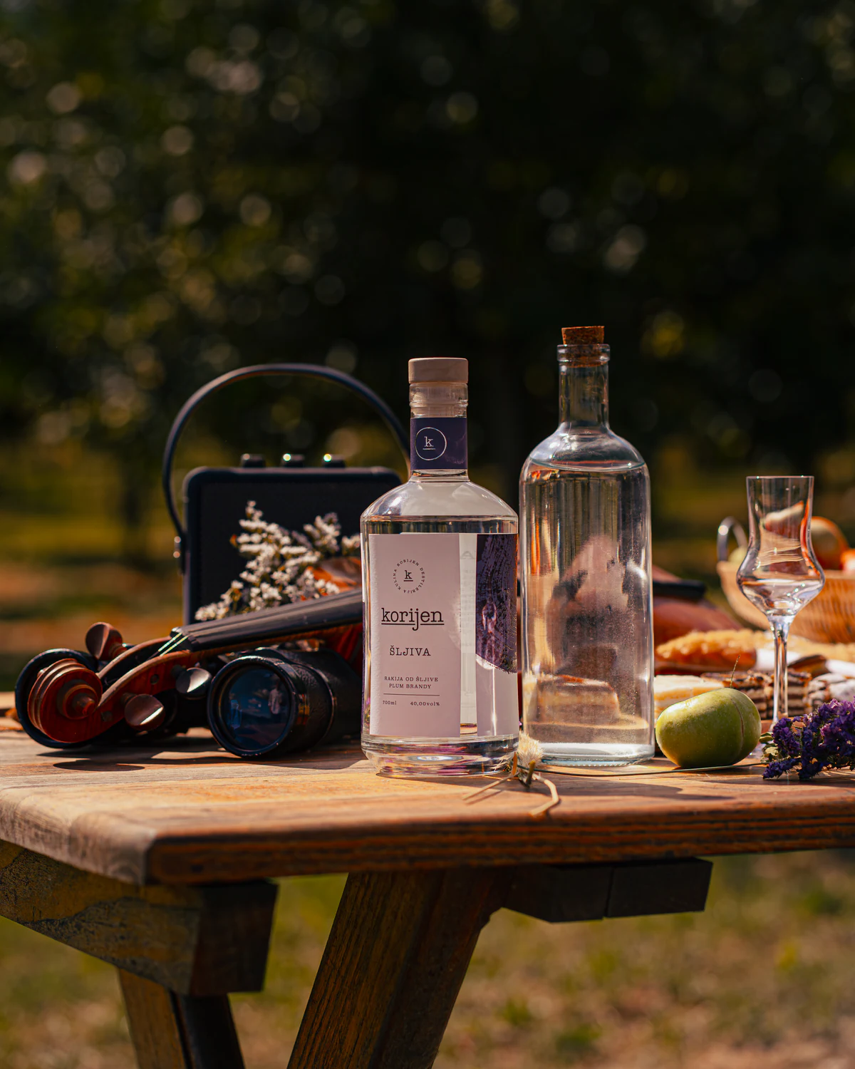 Korijen plum bottle and tasting glass photographed outdoors with objects connected to music and local life.