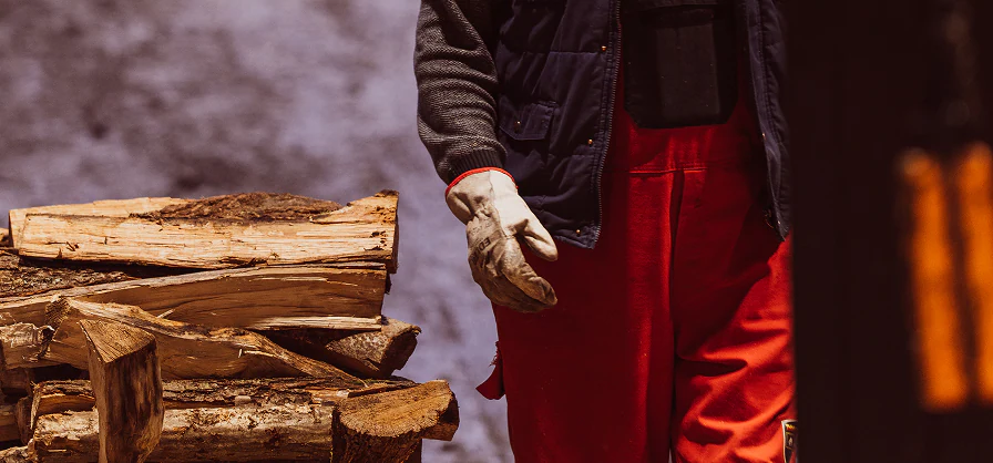 Split wood and distillery worker beside the fire used in the rakija-making process.