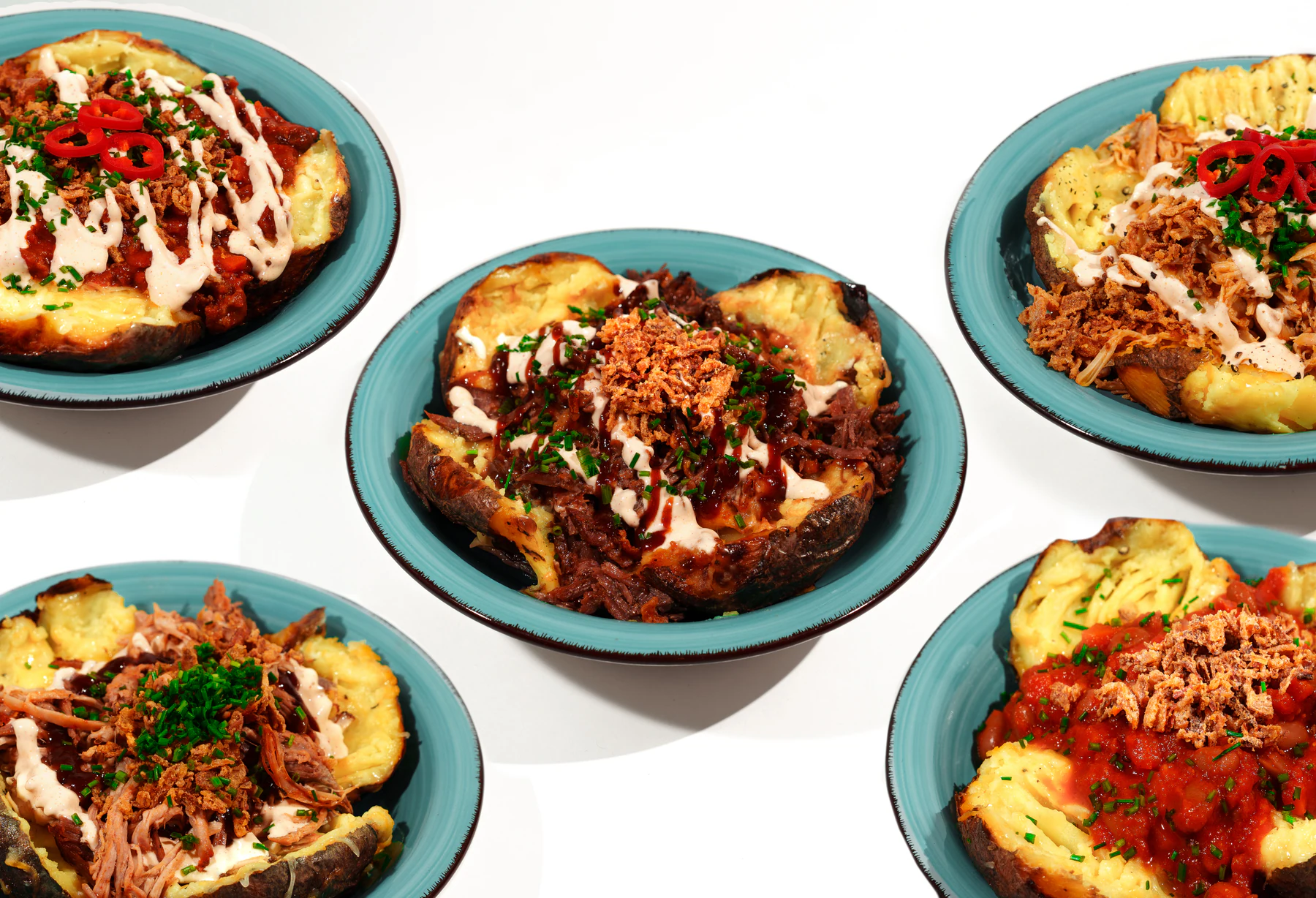 Four Krumpir&Co baked potato dishes arranged on a clean white surface for clear menu comparison.