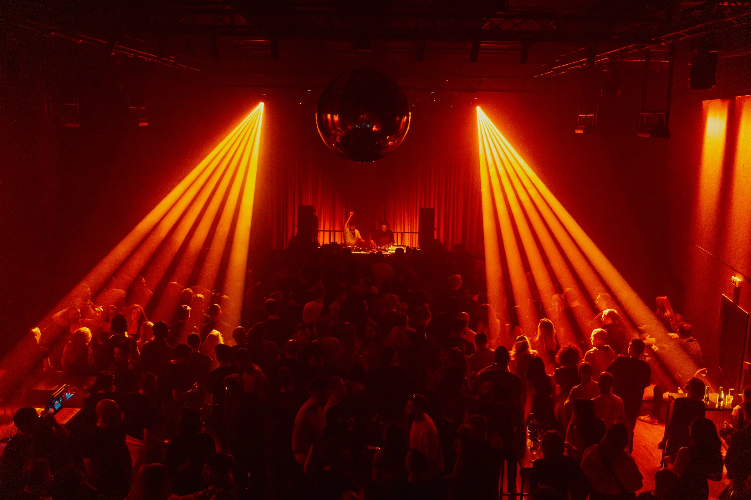 Peti Kupe crowd framed by symmetrical amber light beams during a club night in Zagreb.
