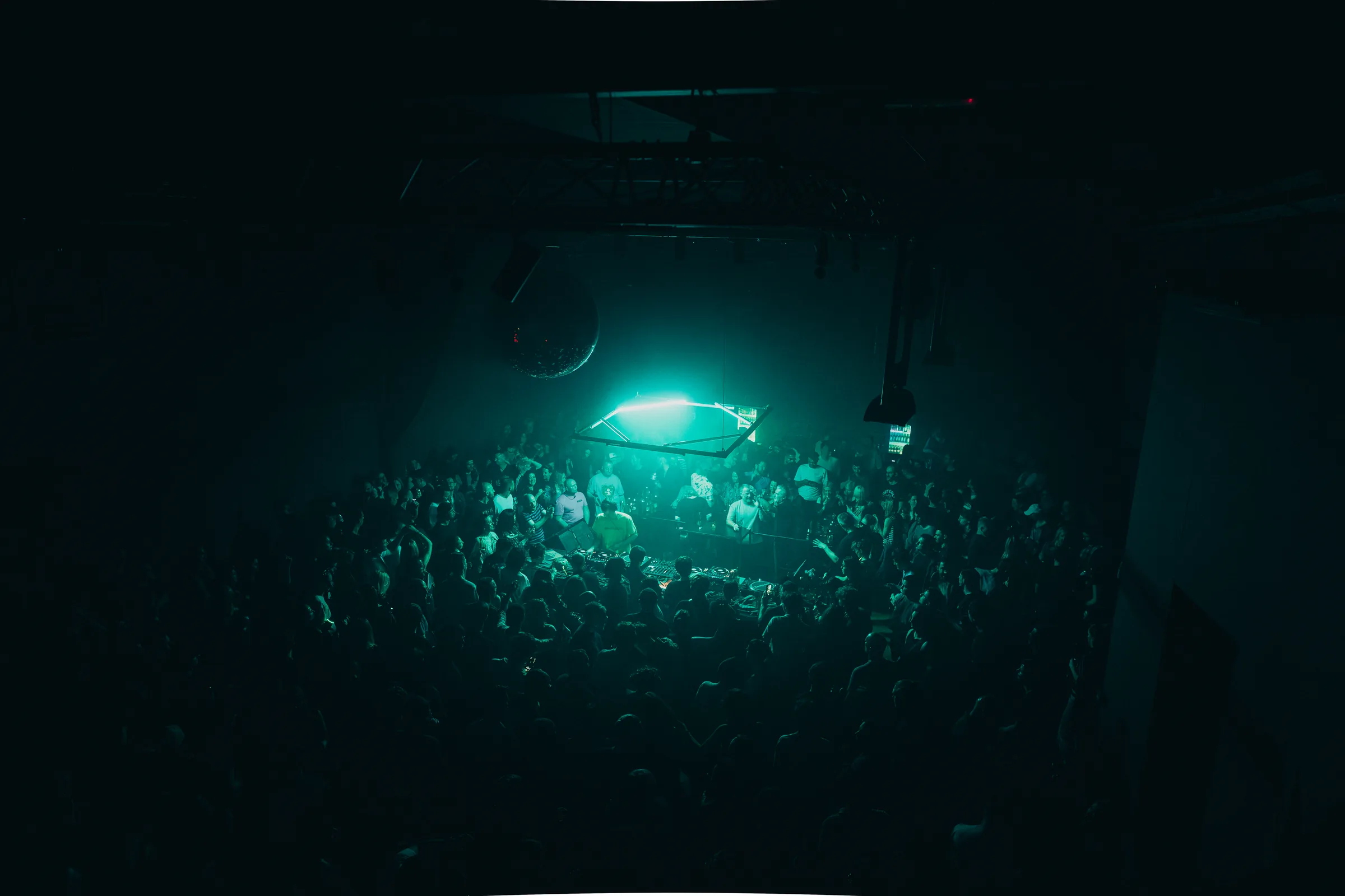 Crowd beneath a disco ball and cyan light at the Peti Kupe anniversary.