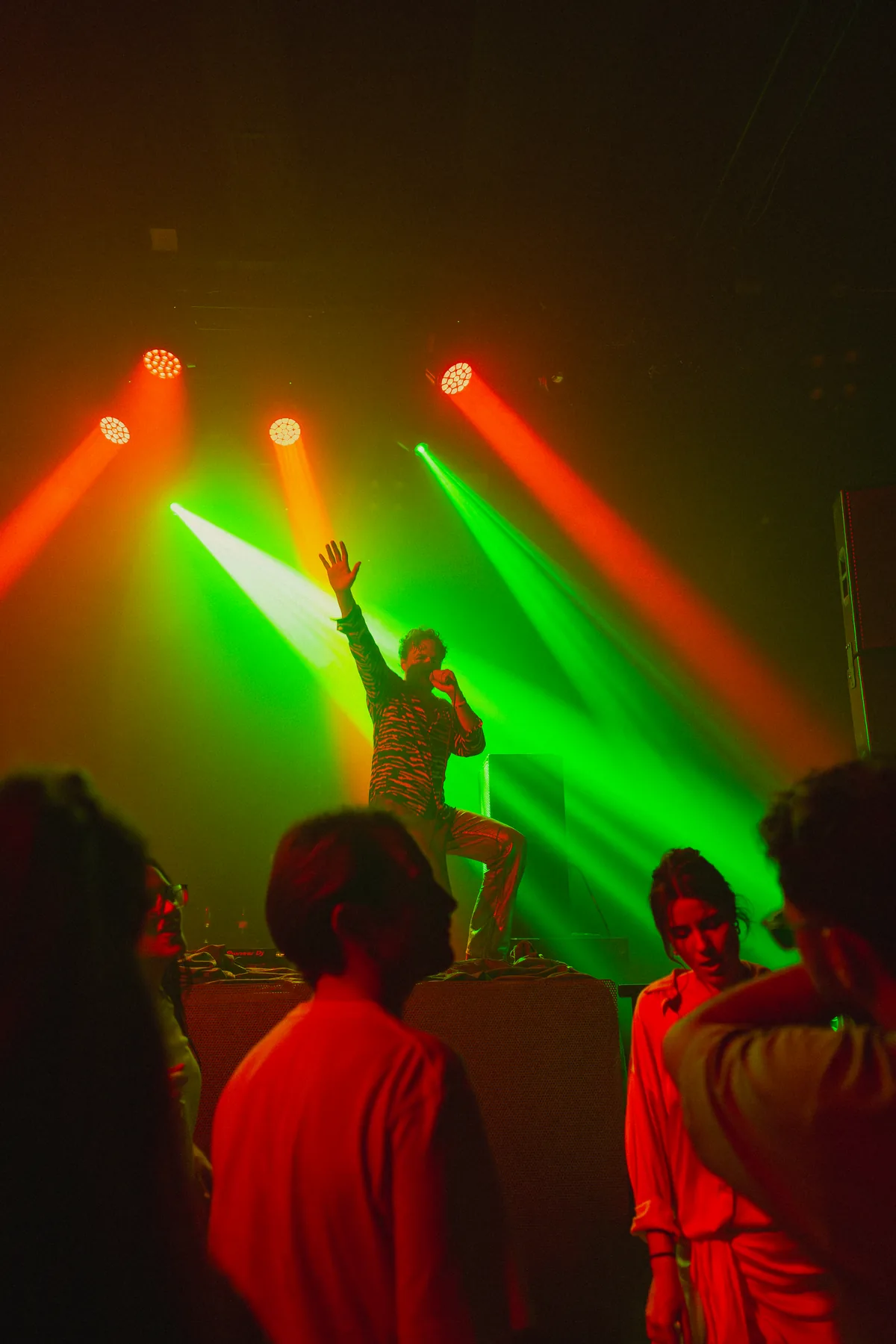 Performer on stage at Peti Kupe lit by green and red light.