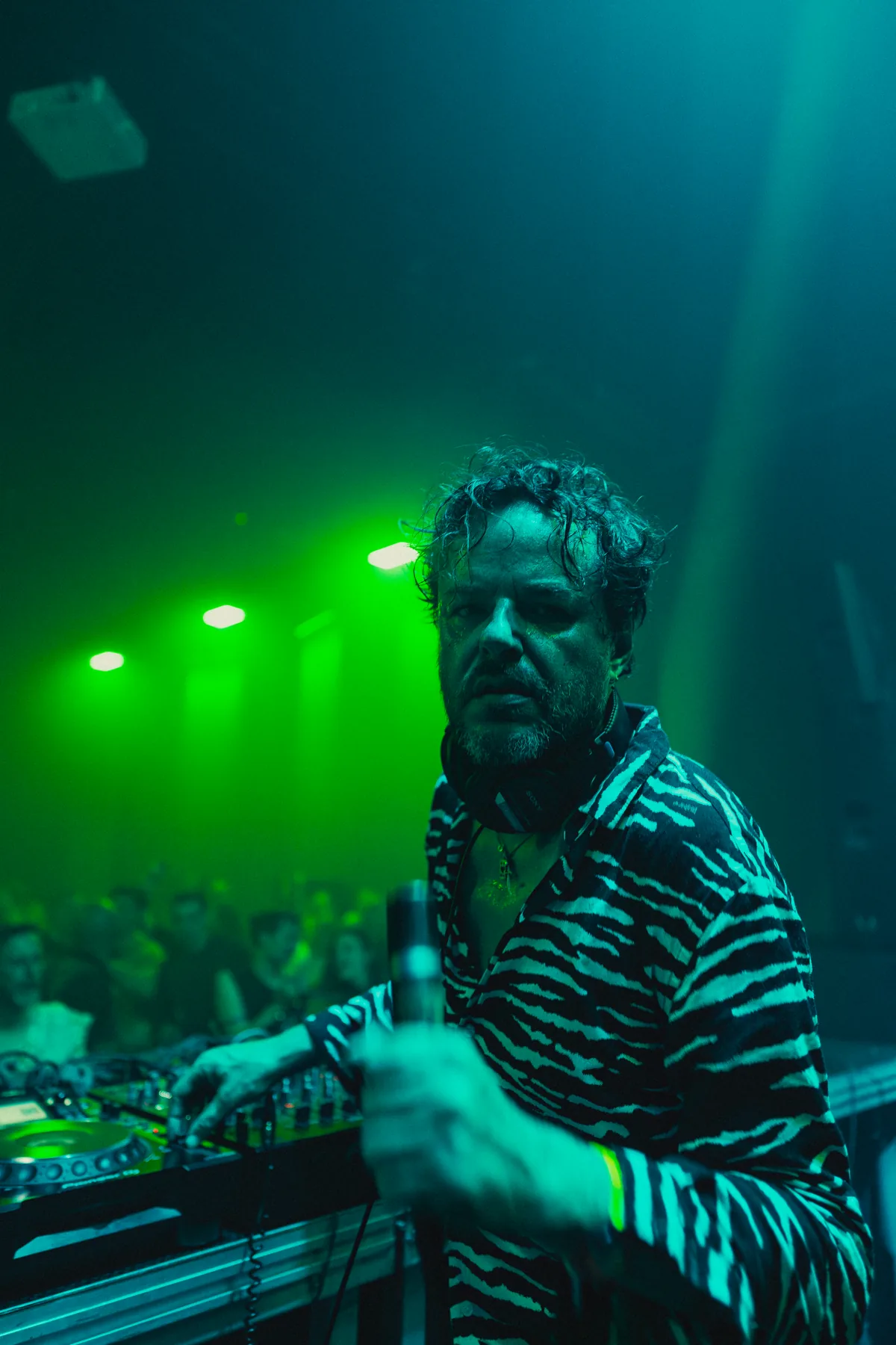 Close portrait of a performer under green stage light at Peti Kupe.