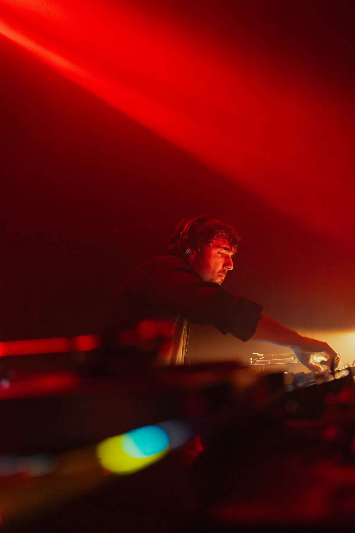 Close portrait of a DJ under warm red light at Peti Kupe.